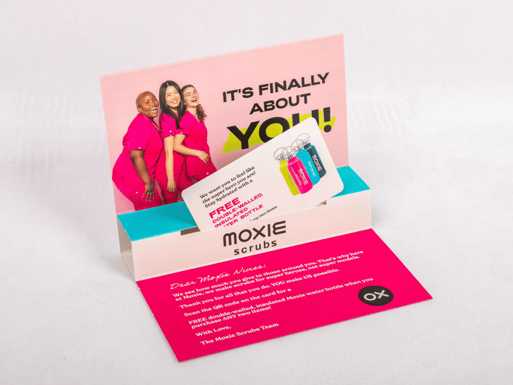 A pink business card featuring an image of two women, designed for dimensional mailers.
